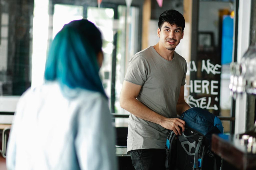 Photo of young man speaking to a young woman in a cafe/bar